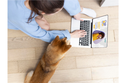 Pessoa usando um computador com seu cachorro ao lado.