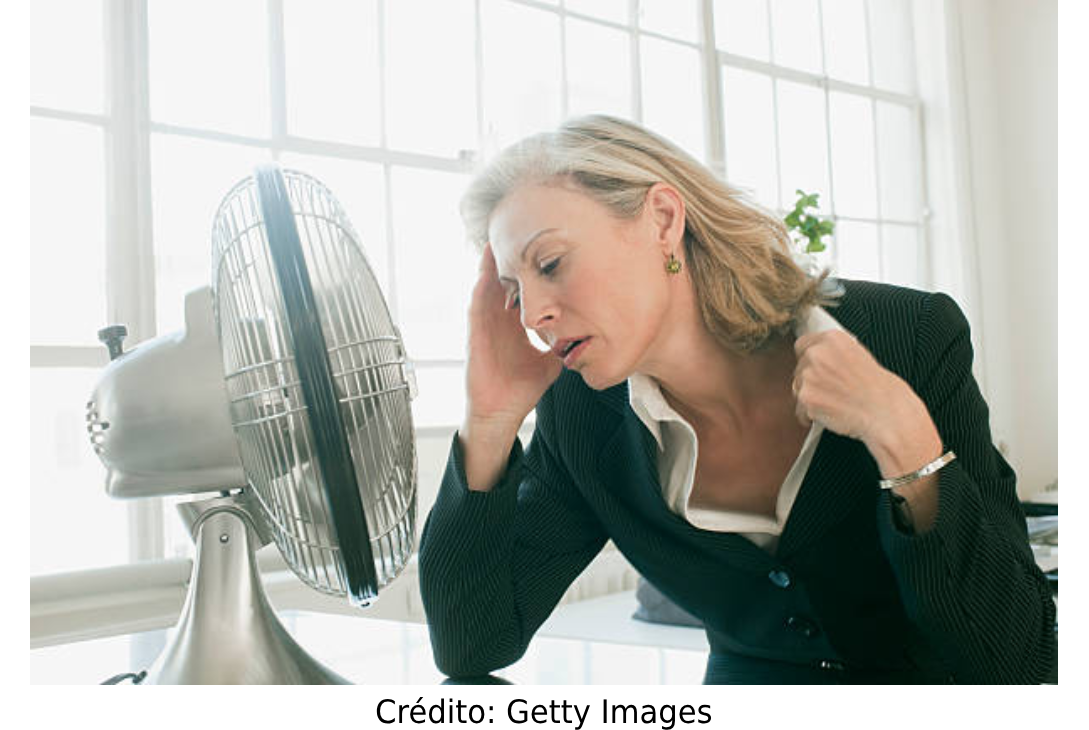 Foto de uma mulher passando calor no trabalho.