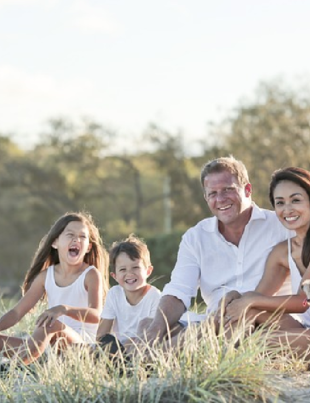 Imagem de uma família feliz sentada num gramado.