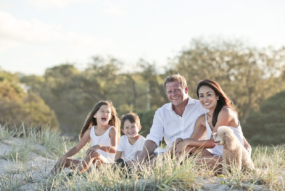 Imagem de uma família feliz sentada num gramado.