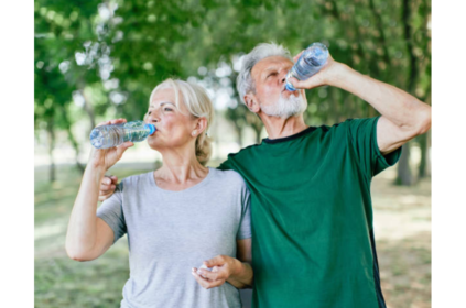 Foto de dois idosos bebendo água em um parque.