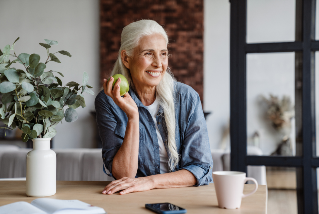 Imagem ilustrativa de uma mulher idossa com uma fruta nas mãos.
