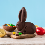 Foto ilustrativa de um coelho de chocolate cercados de ovos de páscoa.