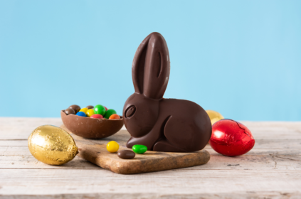 Foto ilustrativa de um coelho de chocolate cercados de ovos de páscoa.