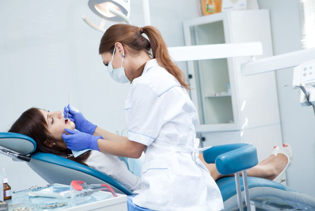 Foto ilustrativa de uma dentista realizando procedimentos dentais.