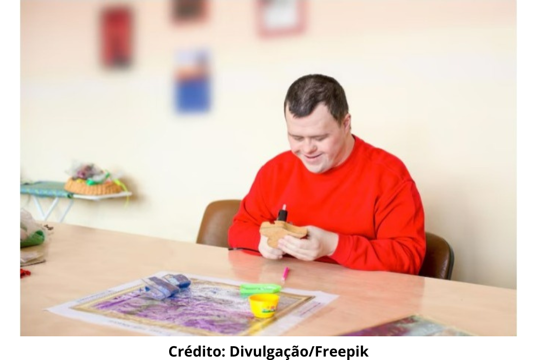 Foto ilustrativa de uma pessoa adulta com Síndrome de Down realizando atividades durante terapia ocupacional.