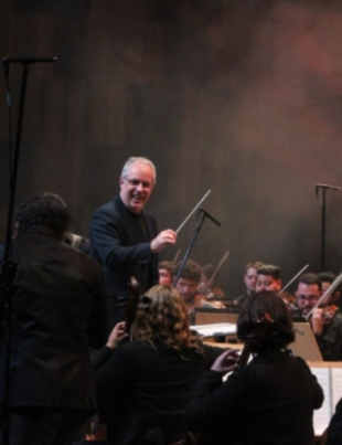 Foto de Edilson Ventureli regendo a Orquestra Sinfônica Heliópolis durante concerto no Teatro B32.