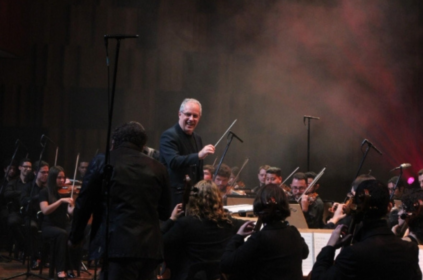 Foto de Edilson Ventureli regendo a Orquestra Sinfônica Heliópolis durante concerto no Teatro B32.