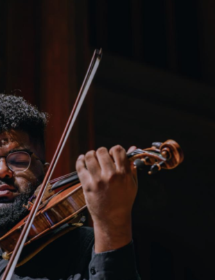 Foto de músico da Orquestra ALMAI se apresentando.