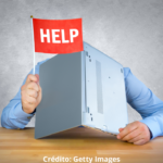 Imagem ilustrativa de uma pessoa com a cabeça escondida entre um notebook aberto pedindo por ajuda.