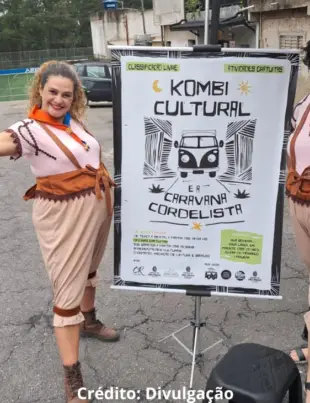 Foto de membros da Kombi Cultural em frente ao banner de divulgação do projeto.