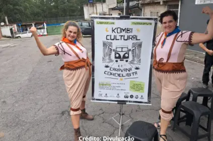 Foto de membros da Kombi Cultural em frente ao banner de divulgação do projeto.