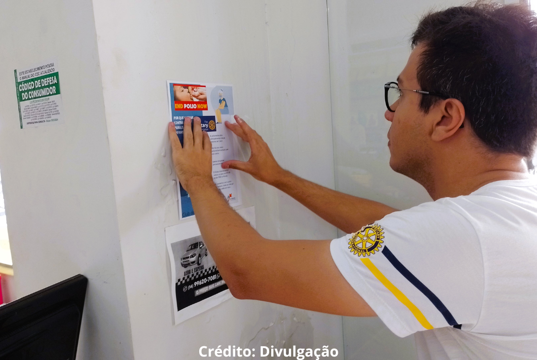 Roriariano vera-cruzense pregando cartaz em estabelecimento comercial.