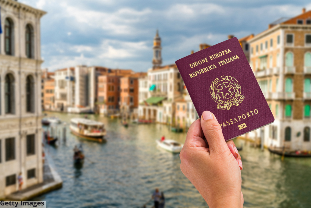 Imagem ilustrativa de uma mão segurando um passaparte italiano erm frente à cidade Italiana.