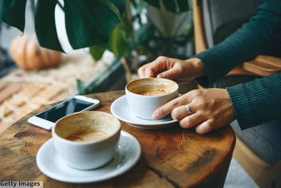 Imagem ilustrativa de uma pessoa não identificada tomando café sentado numa mesa.