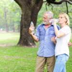 Imageme xclusivo de um casal de idosos no parque bebendo água.