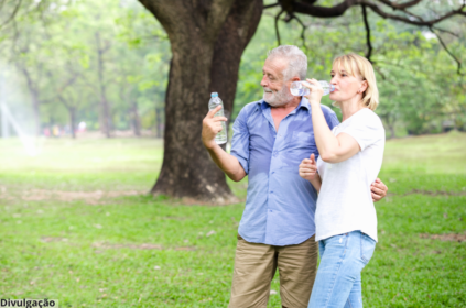 Imageme xclusivo de um casal de idosos no parque bebendo água.