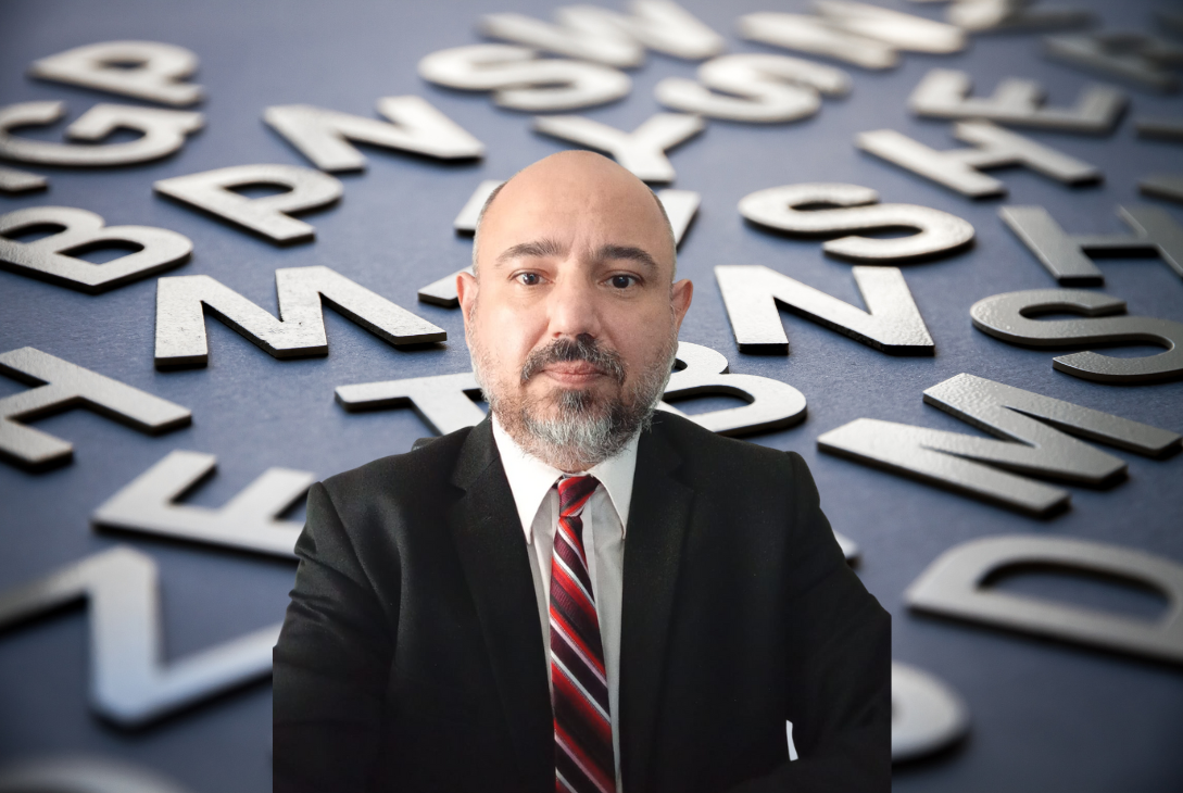 Imagem-montagem da foto do autor do artigo em um fundo com várias letras..