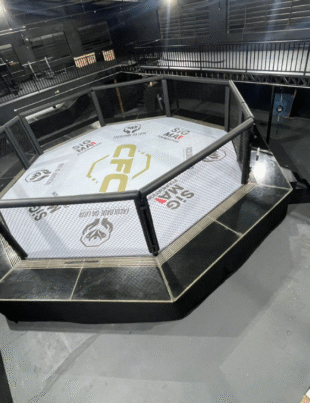 Foto do octógono principal da Faculdade da Luta, novo centro esportivo e educacional inaugurado em Heliópolis, São Paulo. A arena moderna e equipada reflete o compromisso do projeto com a formação cidadã por meio das artes marciais, educação e saúde.