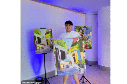 Foto do artista que mostra orgulhoso alguns de seus quadros que viraram estampas de lenços.