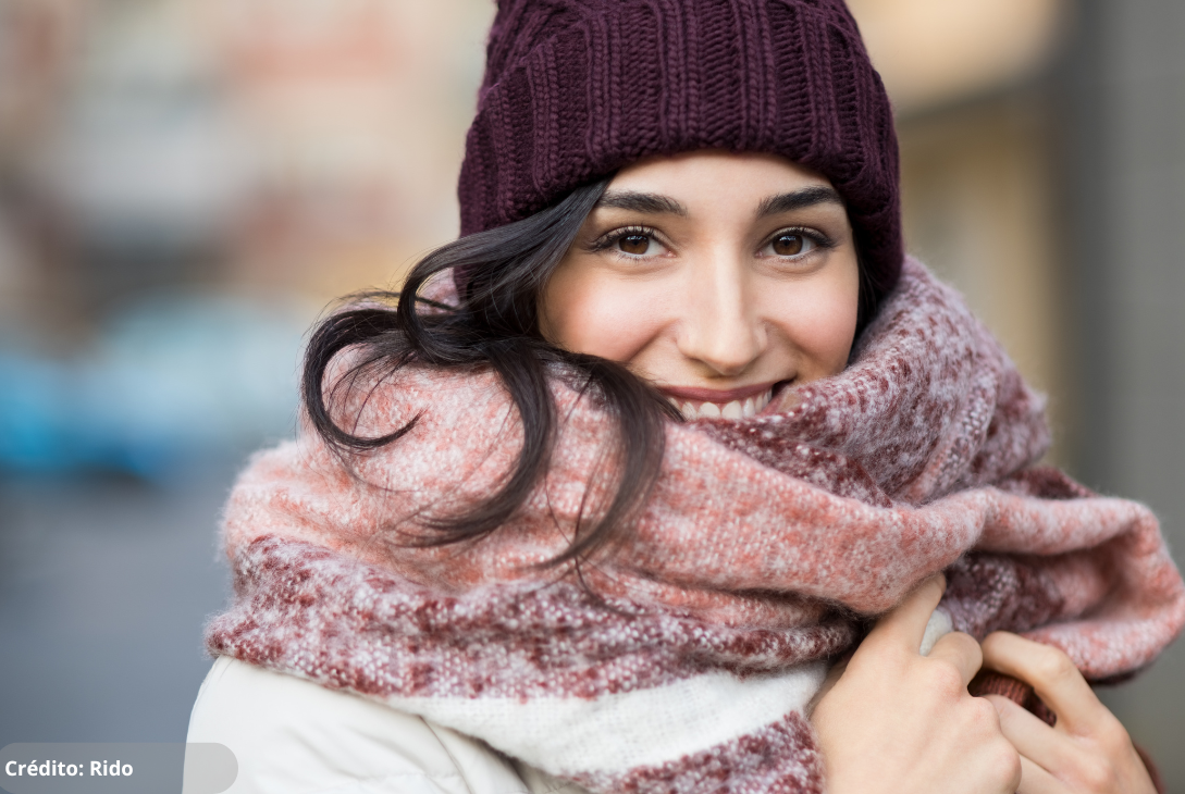 Foto ilustrativa de uma mulher usando roupas de frio na rua.