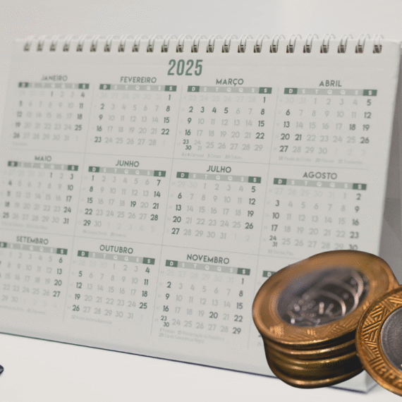 Imagem ilustrativa de um calendário com moedas e uma calculadora do lado.